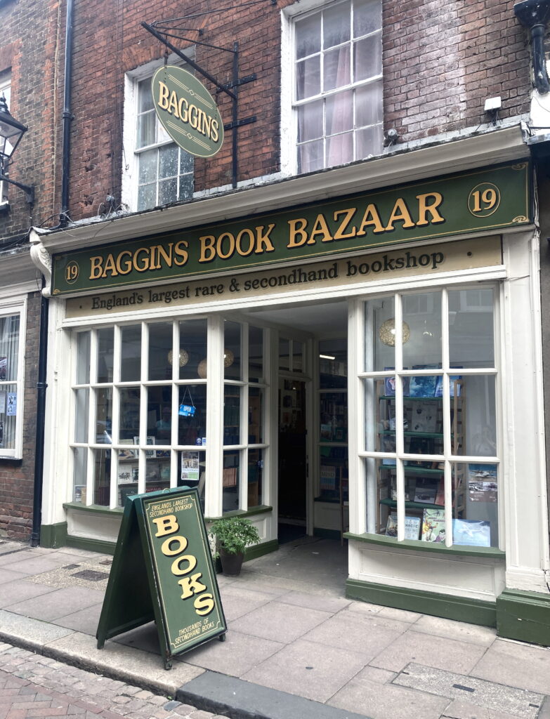 An image of the exterior of Baggins Book Bazaar in Rochester. The shop front is dark green with white windows. 