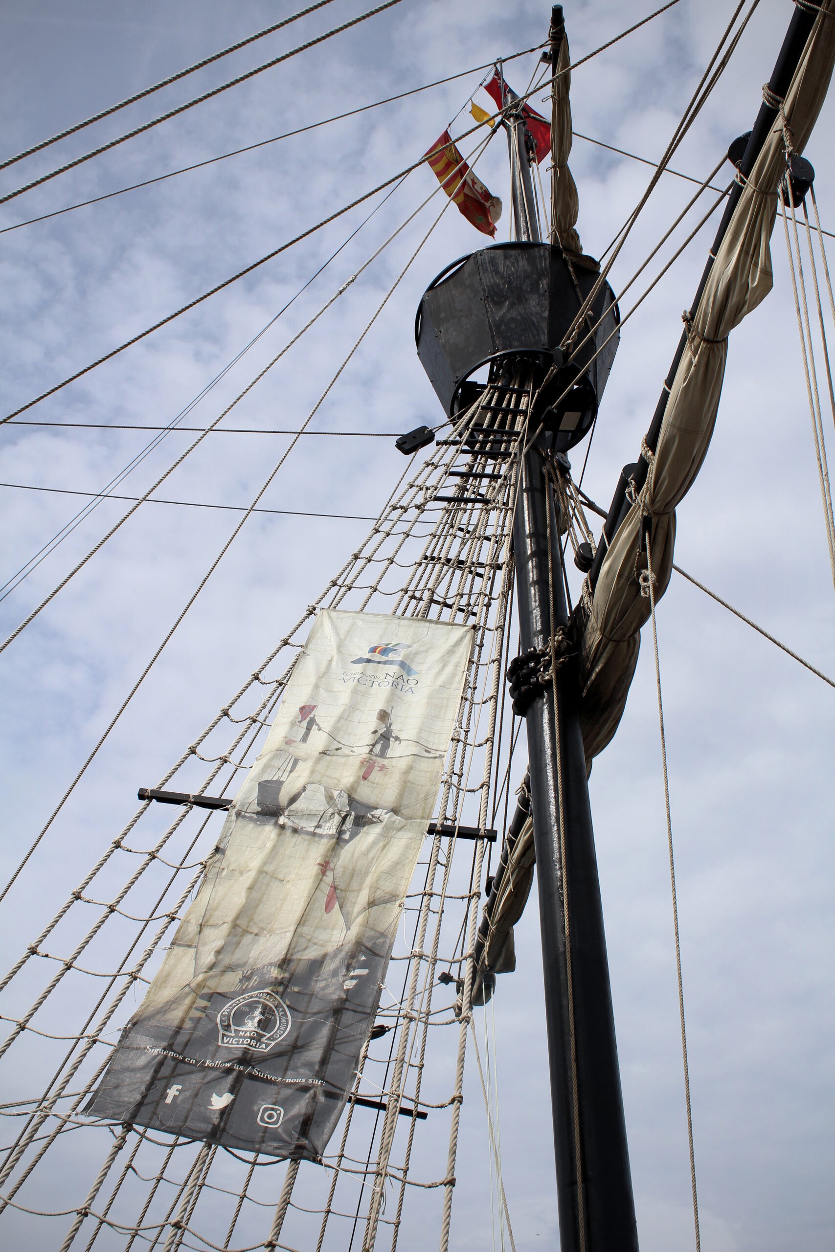 Close up shot of rigging on the Nao Victoria. An advertisement for the Nao Victoria is secured to the rigging.