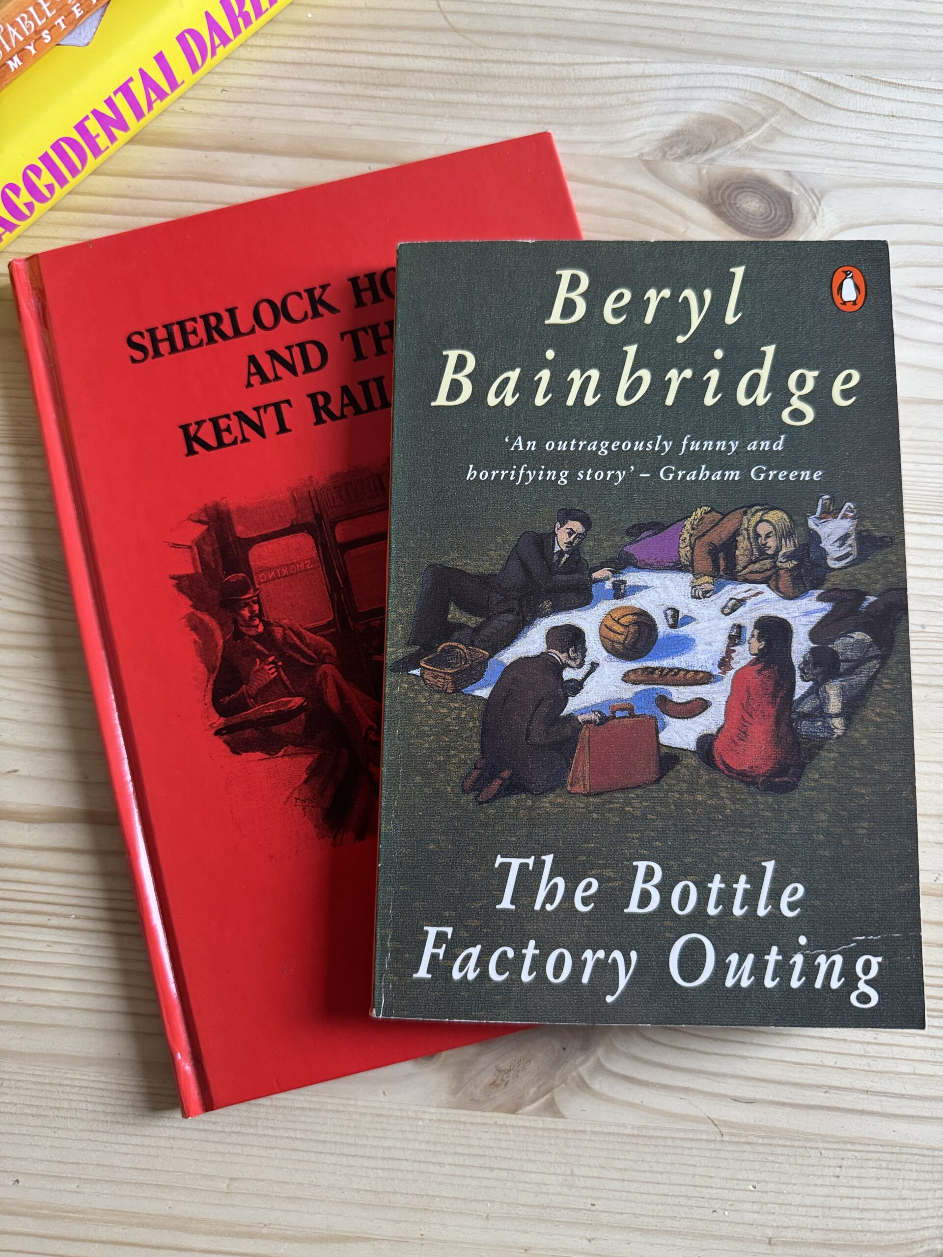 A close up shot of two books, 'Sherlock Holmes and the Kent Railways', and 'The Bottle Factory Outing' on a table.