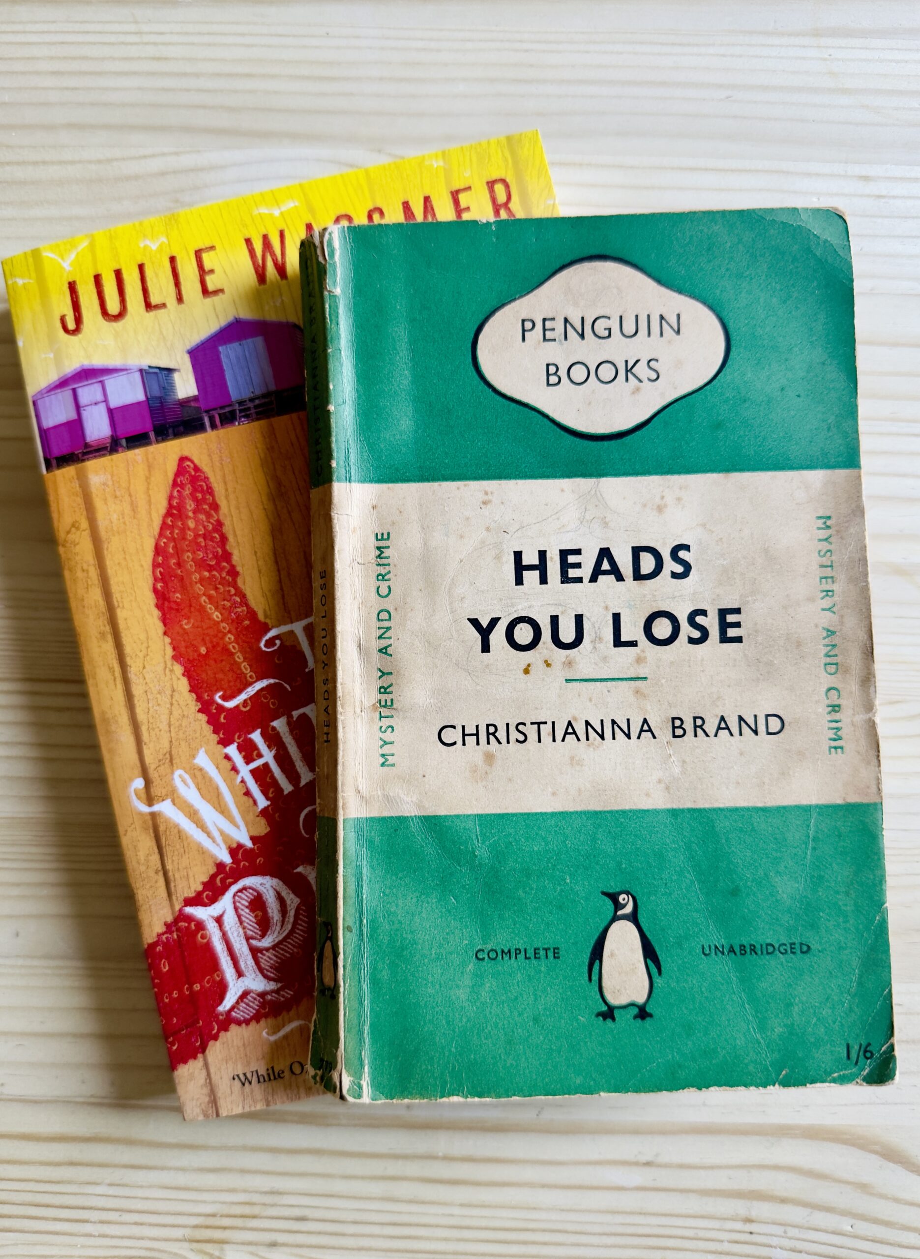 Two books on a table - Whitstable Pearl by Julie Wassmer, and Heads You Lose by Christianna Brand.