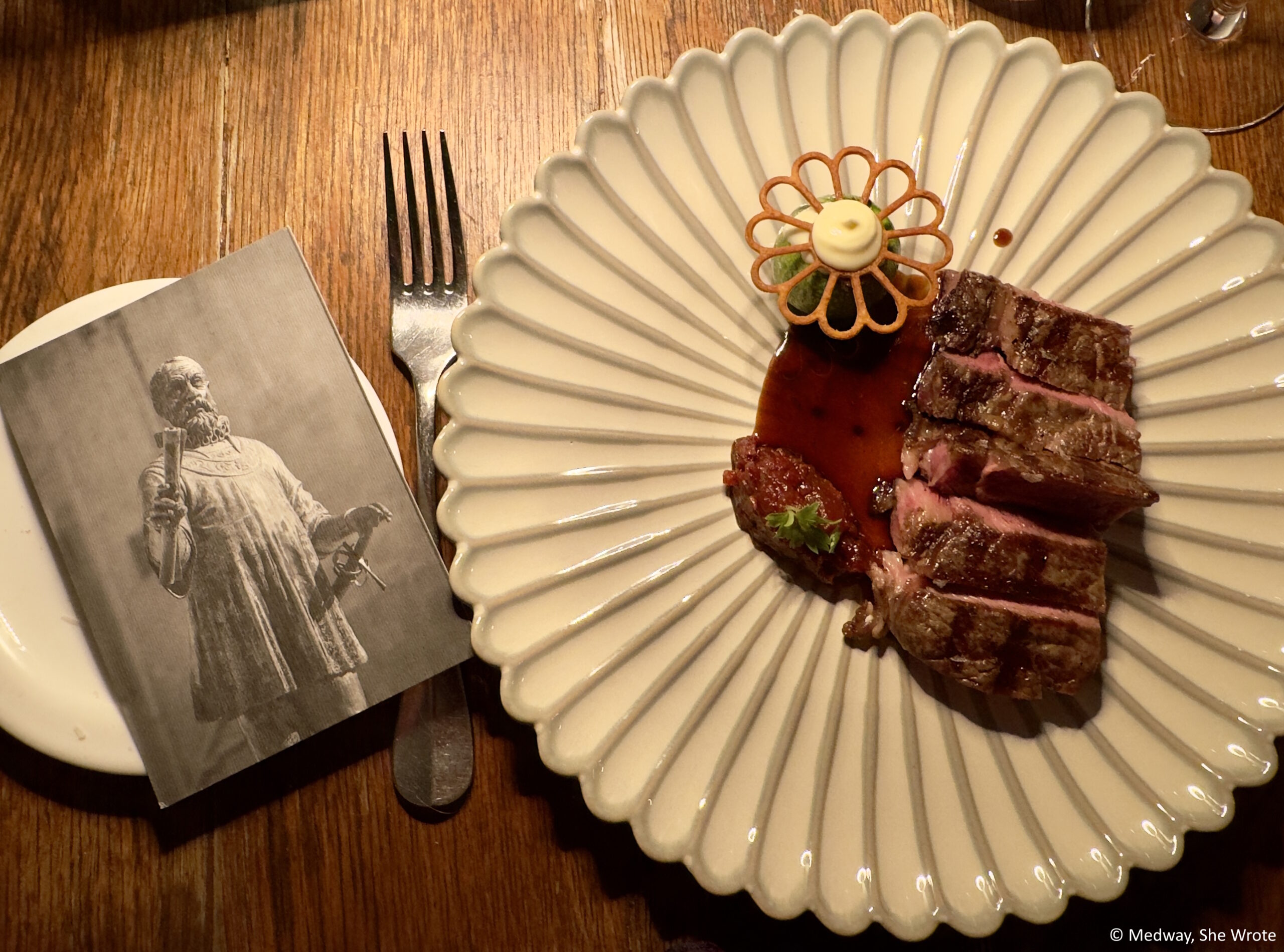 A close up of a main course at The Harbour Club with a black and white postcard of a statute of Jean de Vallette.