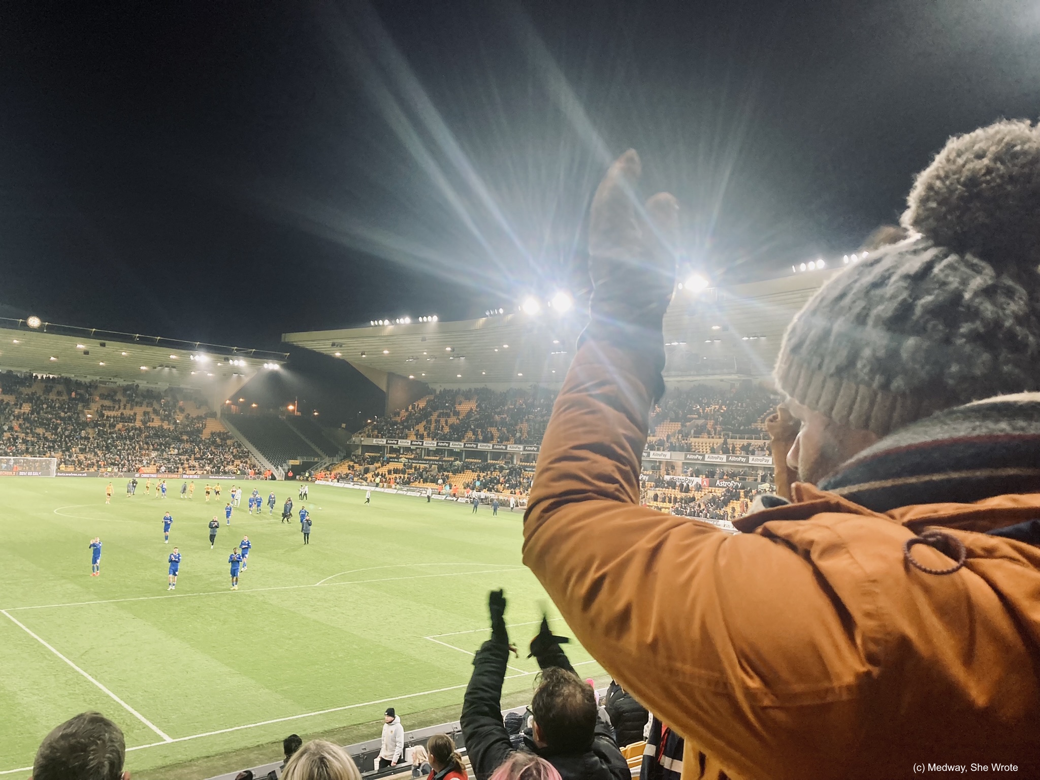 The crowd cheering on Gillingham players on the pitch at Molineux Stadium.