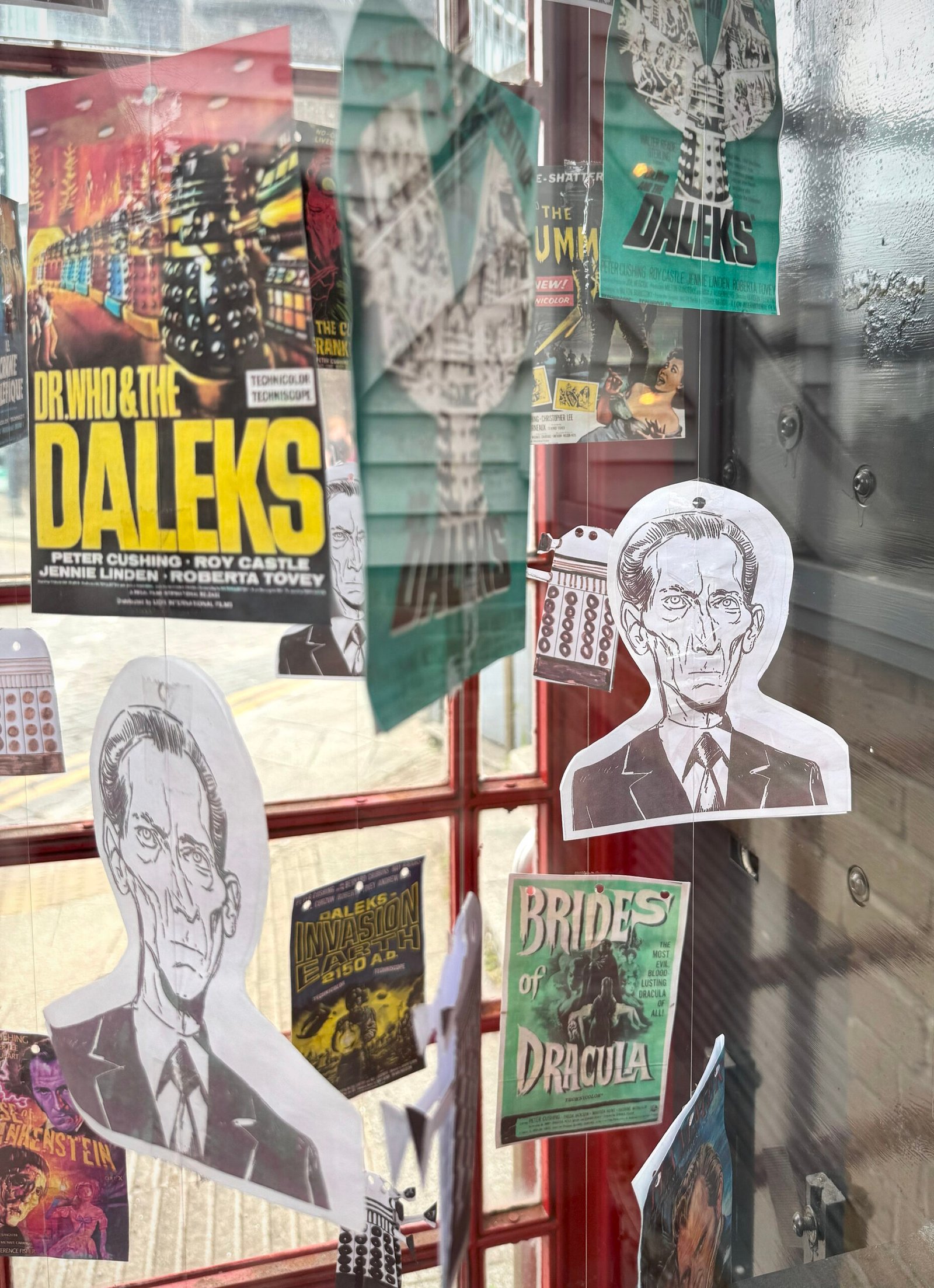 Peter Cushing and Dr. Who-themed art in a phone box in Whitstable. Paper images of daleks, Peter Cushing and colour images of posters from horror and Dr Who movies starring Cushing are hanging inside the phone box.