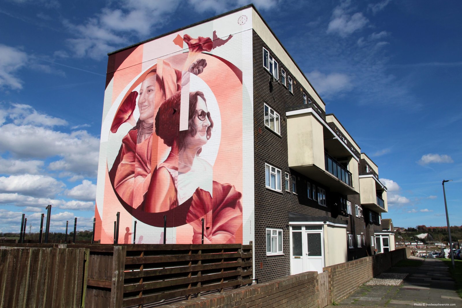 Ricardo Van Zwol's mural of Erica Stuart on the side of a four-story block of flats. The mural is in shades of white and pink and shows Erica Stuart in profile.