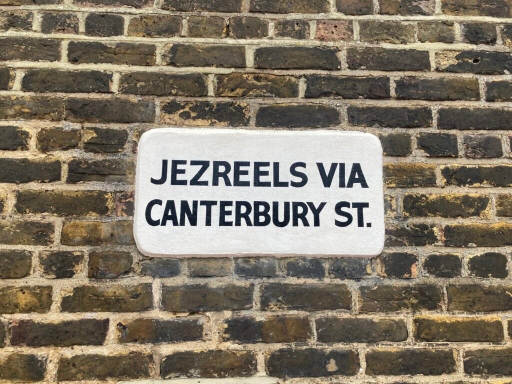 An old bus stop sign on a brick wall near Chatham dockyard. The sign says ‘Jezreels via Canterbury St.’