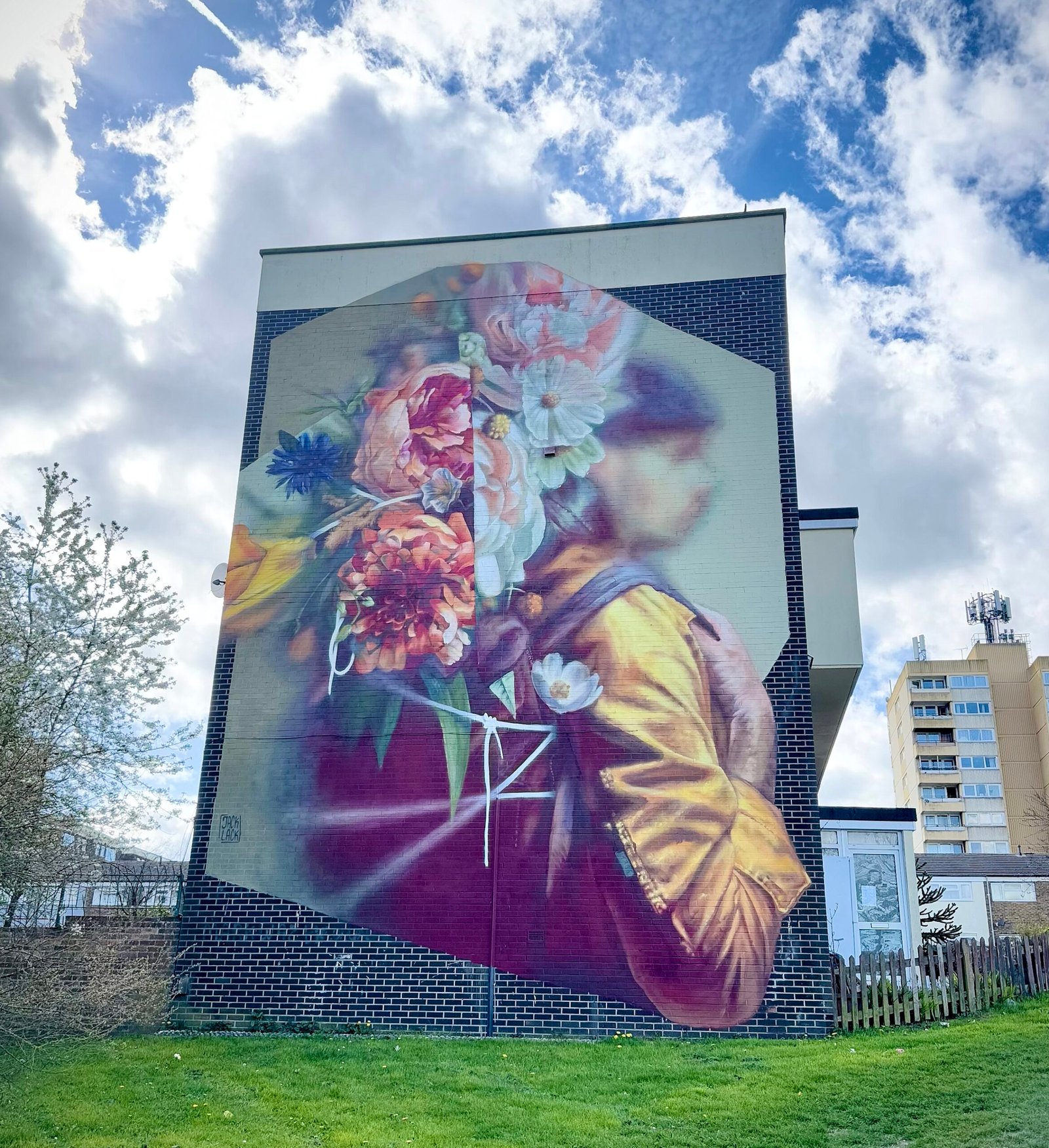 Jack Lack's mural to Henry Charles Lawrence. It shows a woman wearing a yellow jacket with a red bag full of colourful flowers on her back.
