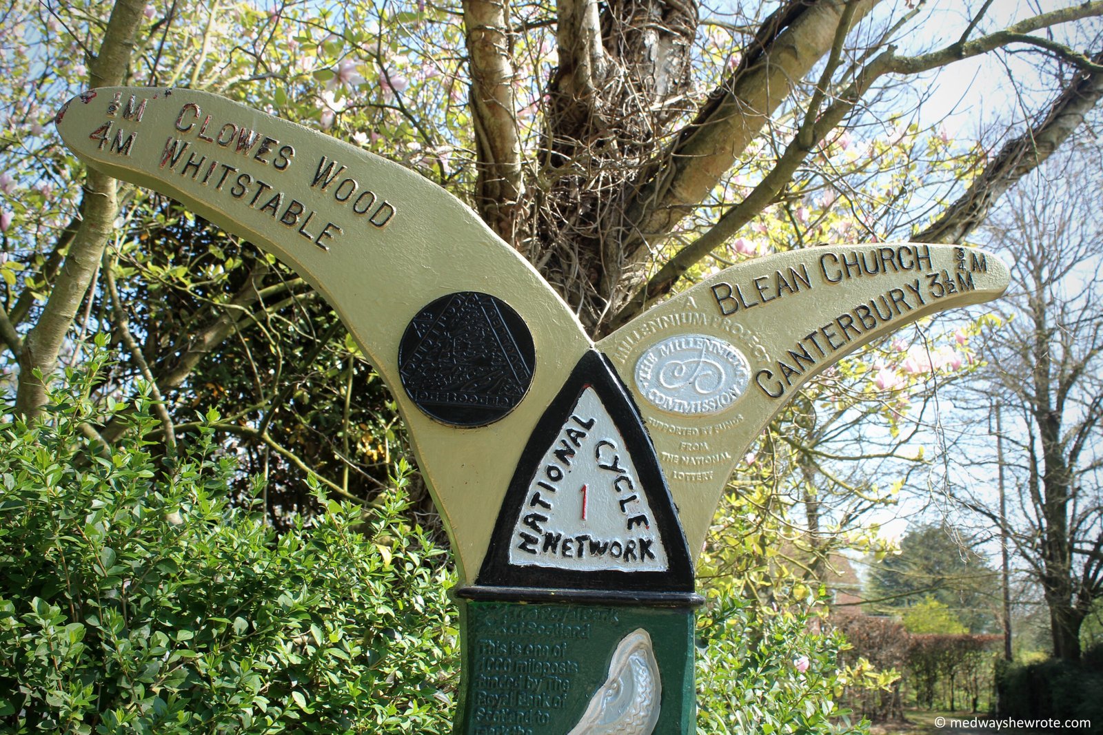 A National Cycle Network pillar showing distances to Whitstable and Clowes Wood on the left side, and distances to Blean Church and Canterbury on the right side.