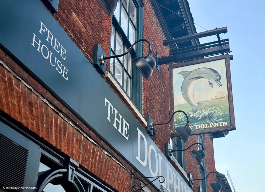 Exterior of The Dolphin pub in Canterbury. The pub sign shows a dolphin leaping out of the sea.
